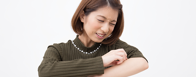 かゆい腕をかく女性